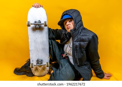 Funny Portrait Of Mature Woman. Lady Having Fun With Skate Dressed As Rapper. Mature Woman On Colored Backgrounds 