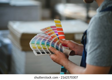 Funny portrait of typographer standing with color swatches at the printing manufacturing.