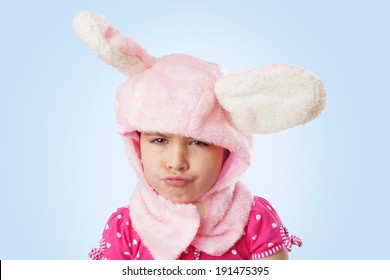 Funny portrait of an unhappy, pouting, little girl in pink bunny costume