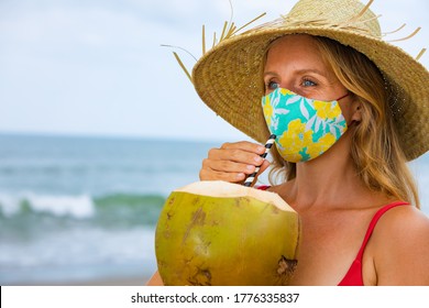 Funny Portrait Of Woman In Straw Hat Drinking Young Coconut On Tropical Sea Beach. New Rules To Wear Cloth Face Covering Mask At Public Places Due Coronavirus COVID 19. Family Holiday, Summer Travel