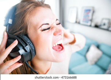 Funny Portrait Young Woman With Headphones Singing And Listening To Music At Home