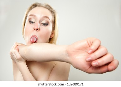 funny portrait of young woman trying to lick her elbow, dorky silly funny face concept