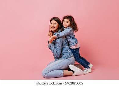 Funny Preteen Kid Embracing Mother. Studio Shot Of Laughing Family In Jeans.