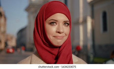 Funny pretty arab woman in red hijab with smartphone looking at camera with happy expression. Portrait of sociable Muslim female tourist.