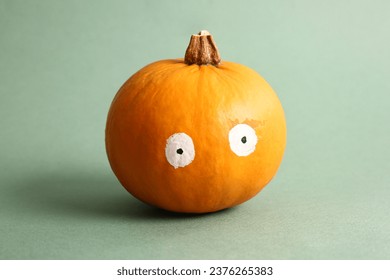 Funny pumpkin with drawn eyes on green background