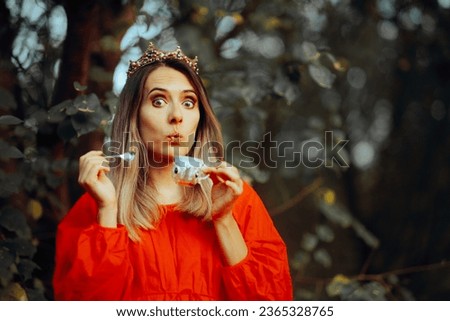 
Funny Queen Drinking Tea Outdoors in her Garden. Woman wearing a princess costume having a warm tea 

