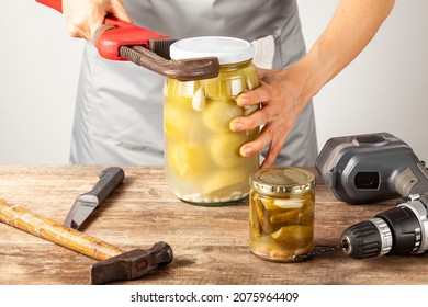 A funny quirky concept image showing a caucasian woman trying to open a jar of pickles. She is trying with tools like drill, knife, wrench and hammer 