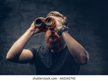 Funny Redhead Bearded Male Looking Through Two Craft Beer Bottle Like Through Binoculars.