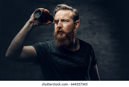 Funny Redhead Bearded Male Looking Through Two Craft Beer Bottle Like Through Binoculars.