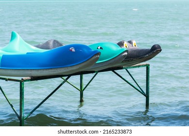 Funny retro dolphin and crocodile shaped kayaks placed on a dock in the blue water on the beach, summer vacation activity, water sport and leisure time concept