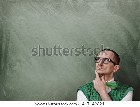 Funny retro nerd thinking over the chalkboard background with copy space