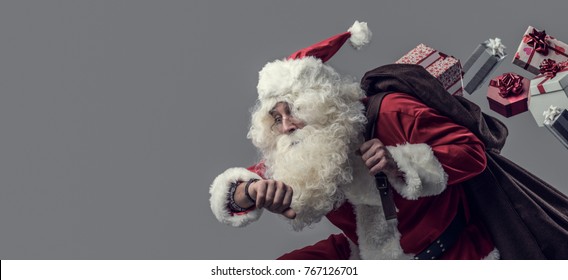 Funny Santa Claus running and delivering Christmas presents, he is checking time and losing gifts from his sack