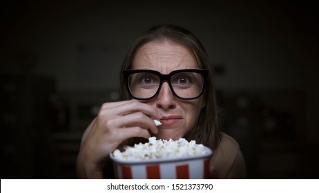 Funny scared woman watching horror movies and eating popcorn at home - Powered by Shutterstock