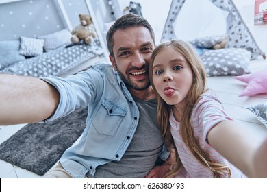                                Funny selfie with dad. Self portrait of young father and his little daughter taking selfie while sitting on the floor in bedroom - Powered by Shutterstock