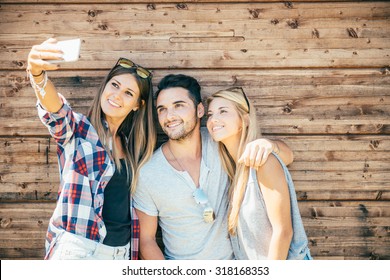 Funny Selfie With Friends. Three Cheerful Young People Making Selfie And Smiling While Standing Outdoors. Wooden Background