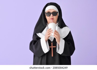 Funny senior nun with soda on color background