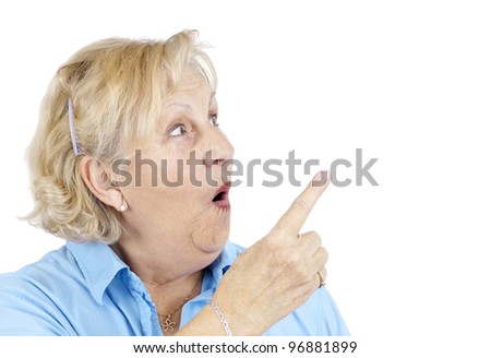 Funny senior woman with surprised face or in shock pointing with her finger at blank space beside her.