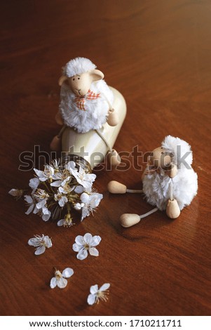 Funny sheep toys playing with colorful bottle and flowers. Humor concept about spring