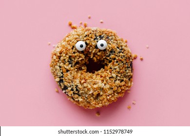 Funny shock face chocolate peanut donut on a pastel pink background, creative minimal Halloween concept