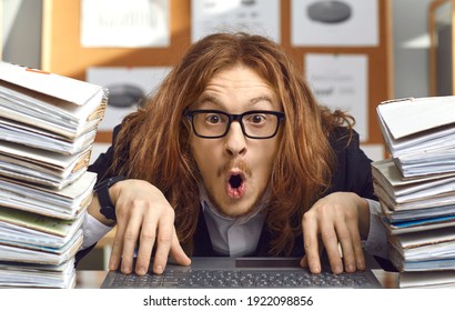 Funny shocked nerdy young accountant sitting at office desk with laptop and folders with paperwork and looking open mouthed at camera with surprised expression on face impressed by crazy money amount - Shutterstock ID 1922098856