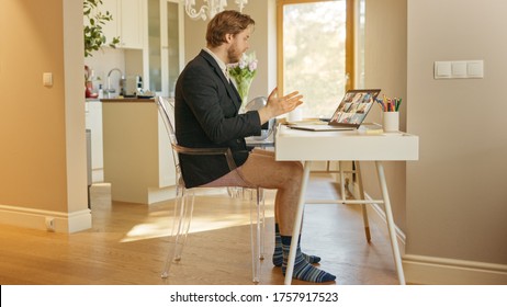 Funny Shot: Businessman Wearing Jacket And No Pants Uses Laptop And Conference Video Call Software App For Board Of Directors Online Meeting. Remote Work, Work At Home, Home Office Concept. Side View