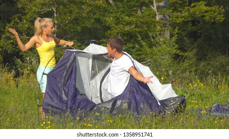 Funny shot of young couple arguing while setting up their tent on a sunny day. Annoyed girlfriend argues with her boyfriend while they set up their campsite by the forest. Young newlyweds fighting. - Powered by Shutterstock