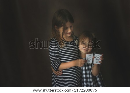 funny sisters girls with painted toys on a dark background, concept childhood and sublimation