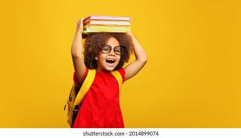 funny smiling Black child school girl and glasses hold books her head  Yellow background