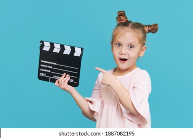 Funny Smiling Child Girl Hold Film Making Clapperboard Isolated On Blue Background. Little Clipmaker, Acting Training. Funny Face. Copy Space For Text.	