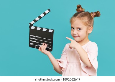 Funny smiling child girl hold film making clapperboard isolated on blue background. Little clipmaker, acting training. Funny face. Copy space for text.	