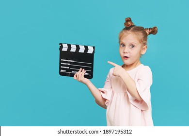 Funny smiling child girl hold film making clapperboard isolated on blue background. Little clipmaker, acting training. Funny face. Copy space for text.	