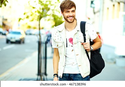 Funny smiling hipster handsome man in stylish summer clothes posing on street background 
