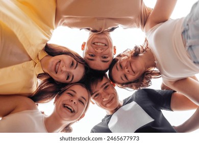 Funny smiling teenagers standing and looking down at camera. Group of cheerful friends in casual clothes having fun together outdoors. Happy laughing boys and girls. Low angle view - Powered by Shutterstock