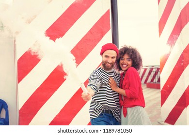 Funny smoke flare. Cheerful young creative couple having fun and laughing while using white smoke flare - Powered by Shutterstock