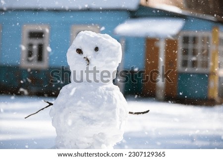 Funny snowman with branches instead of arms and eyes against the background of flying snowflakes.