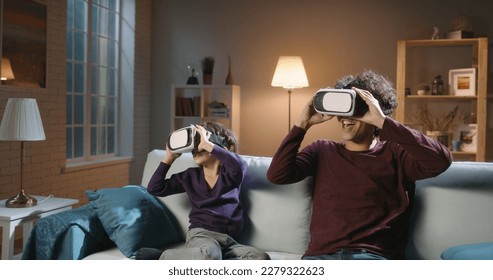 Funny south asian siblings or father and son with curly hair are trying virtual reality headsets, having fun playing video games - modern technologies, family time concept  - Powered by Shutterstock