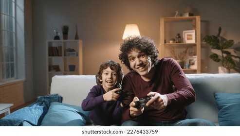 Funny south asian siblings are relaxing together, playing video games in front of tv, father and son expressing emotions while enjoying their hobby - family time concept 