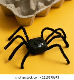 Funny Spider From Egg Carton Packaging On Yellow Background, Square Form. Children's Craft For Halloween Party. Simple DIY, Creative Eco Friendly Idea, Reuse  And Zero Waste Concept.