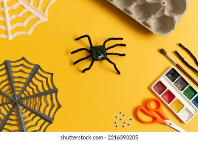 Funny Spider From Egg Carton Packaging, Finished Toy And Materials On Yellow Background. Children's Craft For Halloween Party. Simple DIY, Creative Ecofriendly Idea, Reuse And Zero Waste Concept.