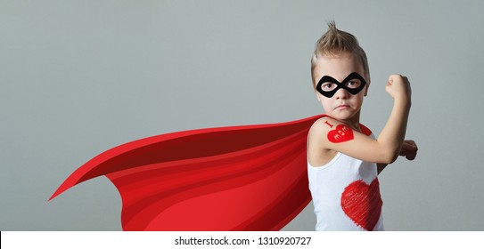 Funny Strong Child Raising Hand In Success Gesture. Little Cool Boy Superhero Loves Mom, Shows Heart. Portrait Confident Kid In Costume Super Hero Expresses Strength, Leadership. Banner, Copy Space.