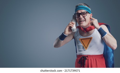 Funny Superhero Making A Phone Call Using An Old Obsolete Cordless Telephone, He Can't Hear The Caller