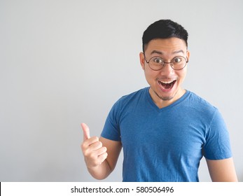 Funny surprised and overjoyed face of Asian man in blue t-shirt and eyeglasses.