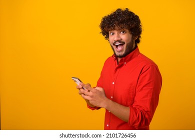Funny surprised trendy guy suddenly read message on his mobile phone and expressing shock amazement, unbelievable news on smartphone. Studio shot isolated