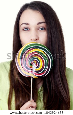 Funny teenage girl eating big lollipop. Happy teenager with colorful caramel candy bonbon isolated on white background in studio.