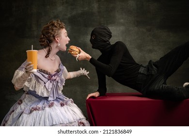 Funny time. Cinematic portrait of young beautiful woman in image of medieval royal person in renaissance style dress and her servant, page isolated on dark vintage background. Comparison of eras