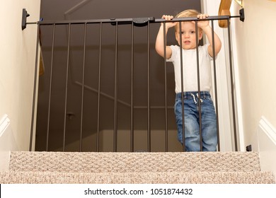 Funny Toddler Approaching Safety Gate Of Stairs.