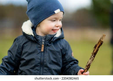 Funny Toddler Boy Having Fun Outdoors On Chilly Winter Day. Child Exploring Nature. Winter Activities For Small Kids.