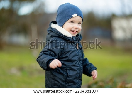 Funny toddler boy having fun outdoors on chilly winter day. Child exploring nature. Winter activities for small kids.