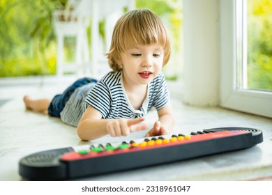 Funny toddler boy playing toy piano at home. Little boy learning to play piano. Child listening to music. Early development for toddlers. Musical education for kids. - Powered by Shutterstock