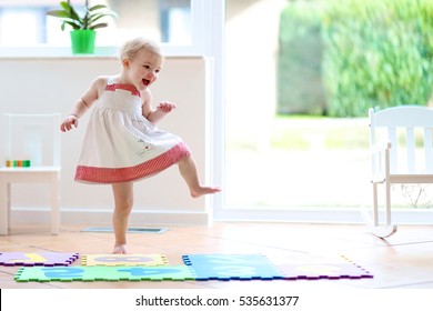 Funny toddler girl dancing indoors. Little child having fun moving and jumping in a sunny white room at home or kindergarten